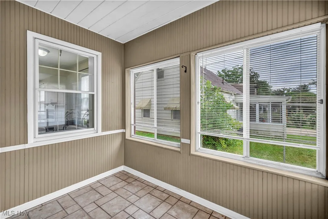 Unfurnished sunroom featuring wood walls and tile patterned floors