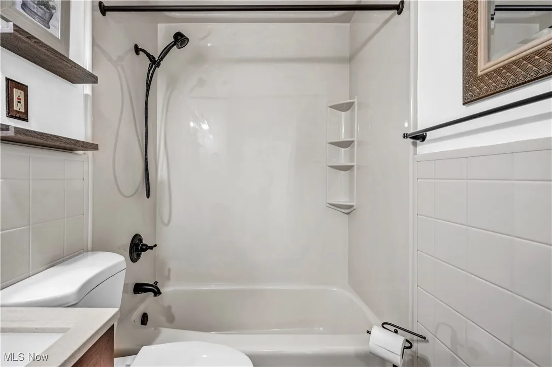 Bathroom featuring tile walls, tub / shower combination, and vanity