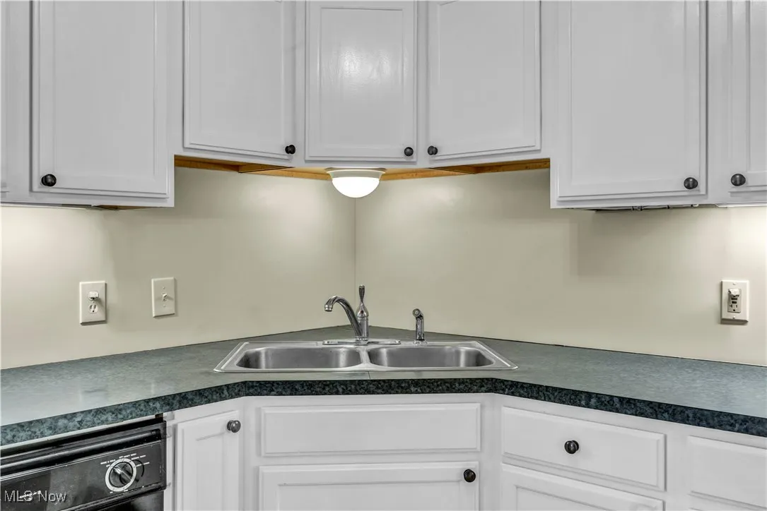 Kitchen with white cabinetry, dark countertops, and dishwasher
