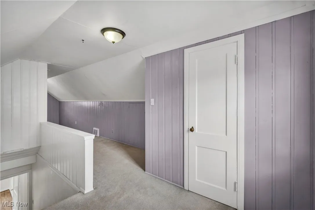 Bonus room with wooden walls, carpet flooring, and vaulted ceiling