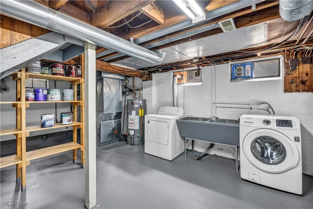 Unfinished below grade area featuring gas water heater, washing machine and dryer, and heating unit