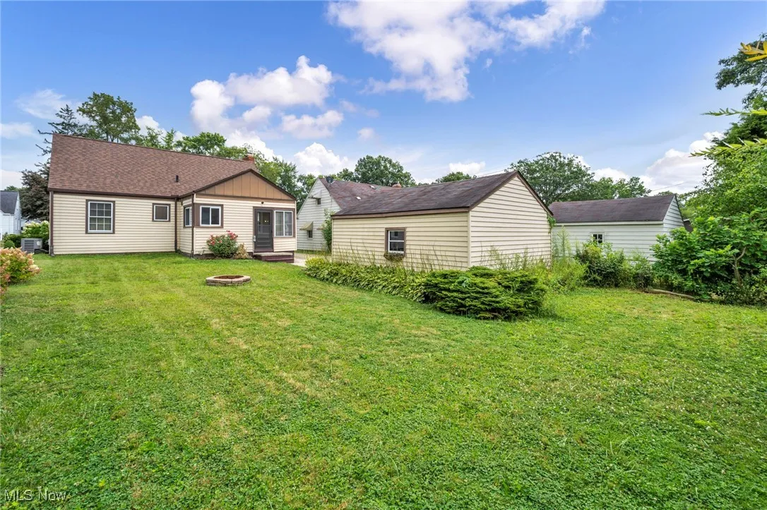 Back of property with a yard, an outdoor fire pit, and roof with shingles