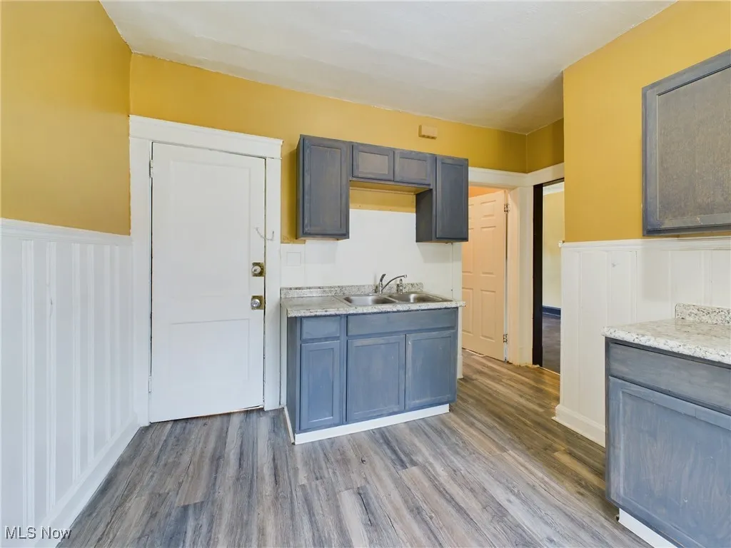 Kitchen featuring a wainscoted wall, a decorative wall, dark wood finished floors, and light countertops