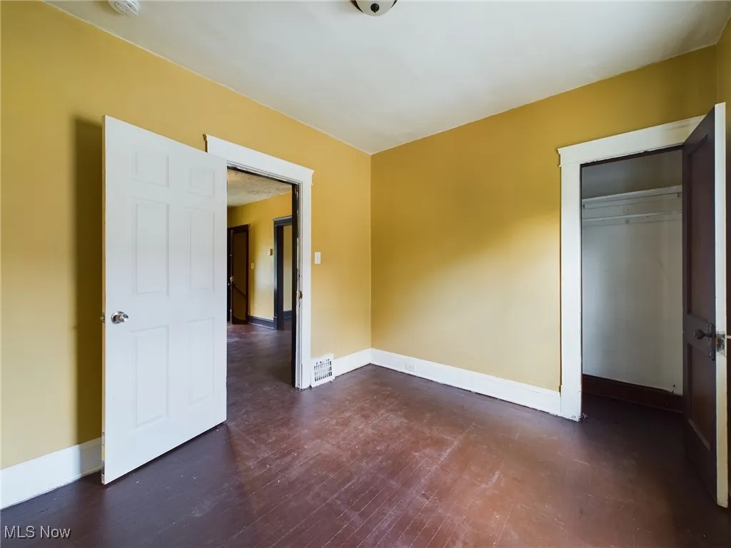 Unfurnished bedroom featuring dark wood finished floors and a closet