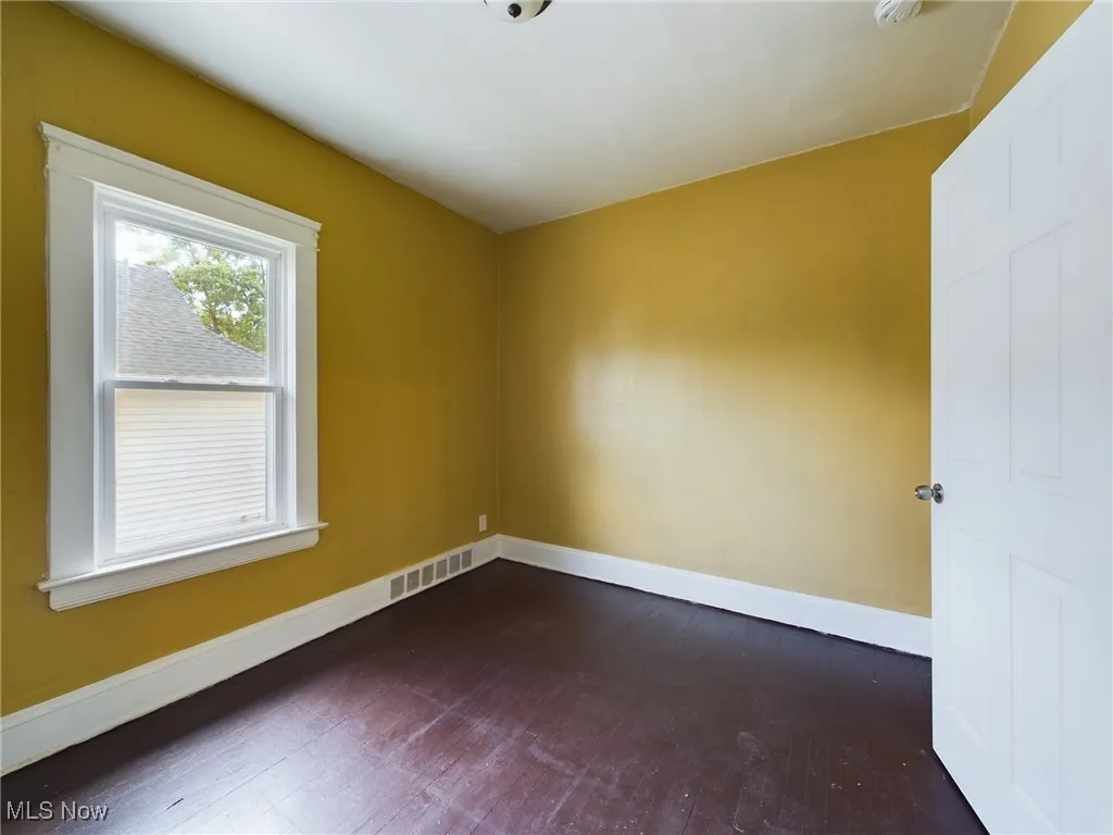 Empty room featuring baseboards and dark wood-type flooring