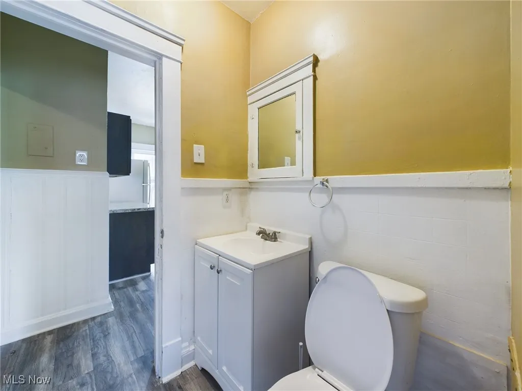 Bathroom with wainscoting, vanity, and dark wood-style flooring