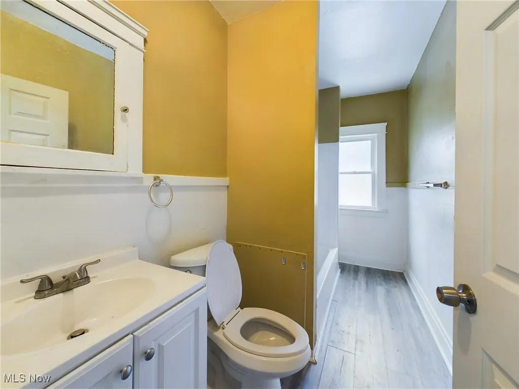 Full bath with vanity and light wood-style floors