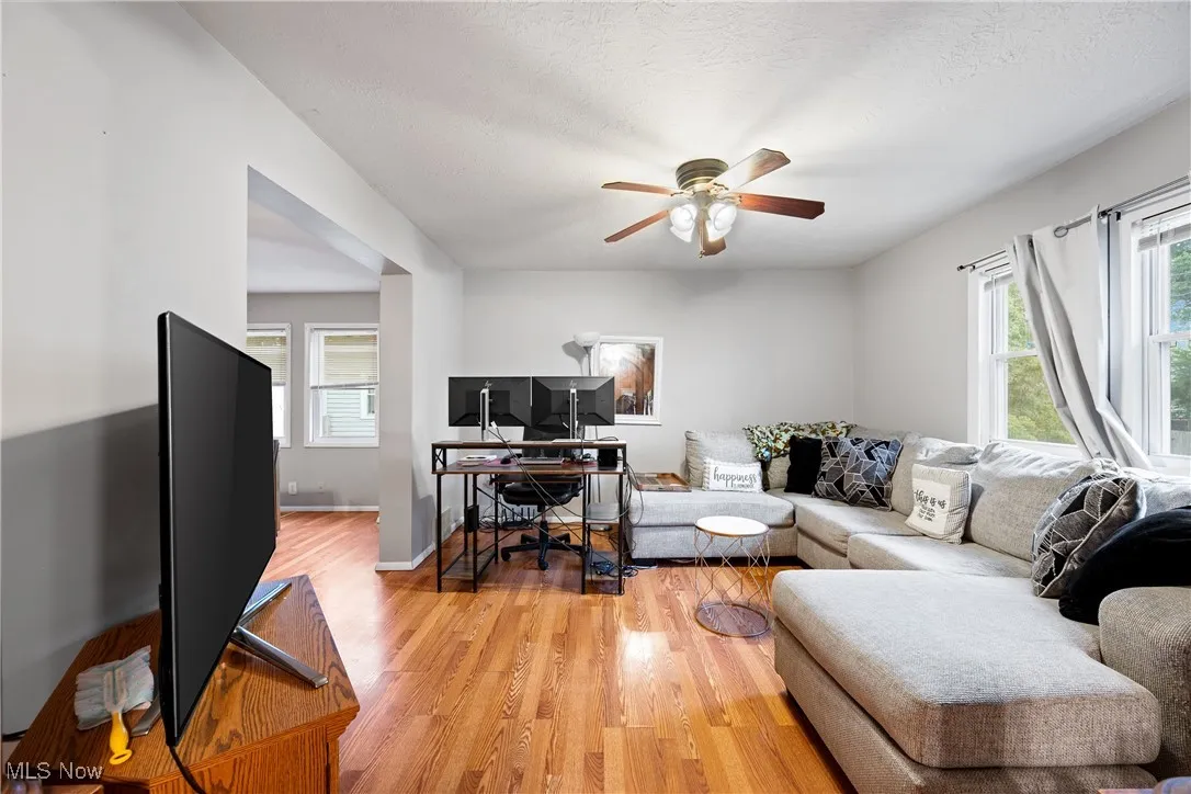 Living area with an office area, light wood-type flooring, a textured ceiling, and a ceiling fan