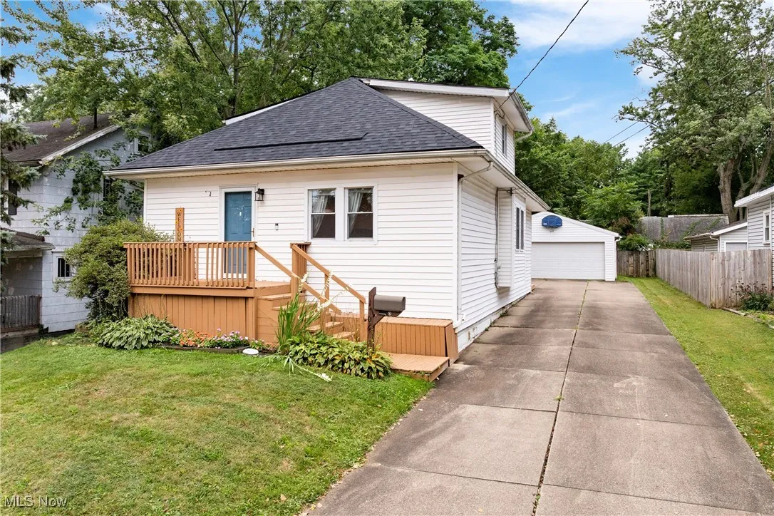 Bungalow-style home featuring a wooden deck, roof with shingles, a garage, and an outdoor structure