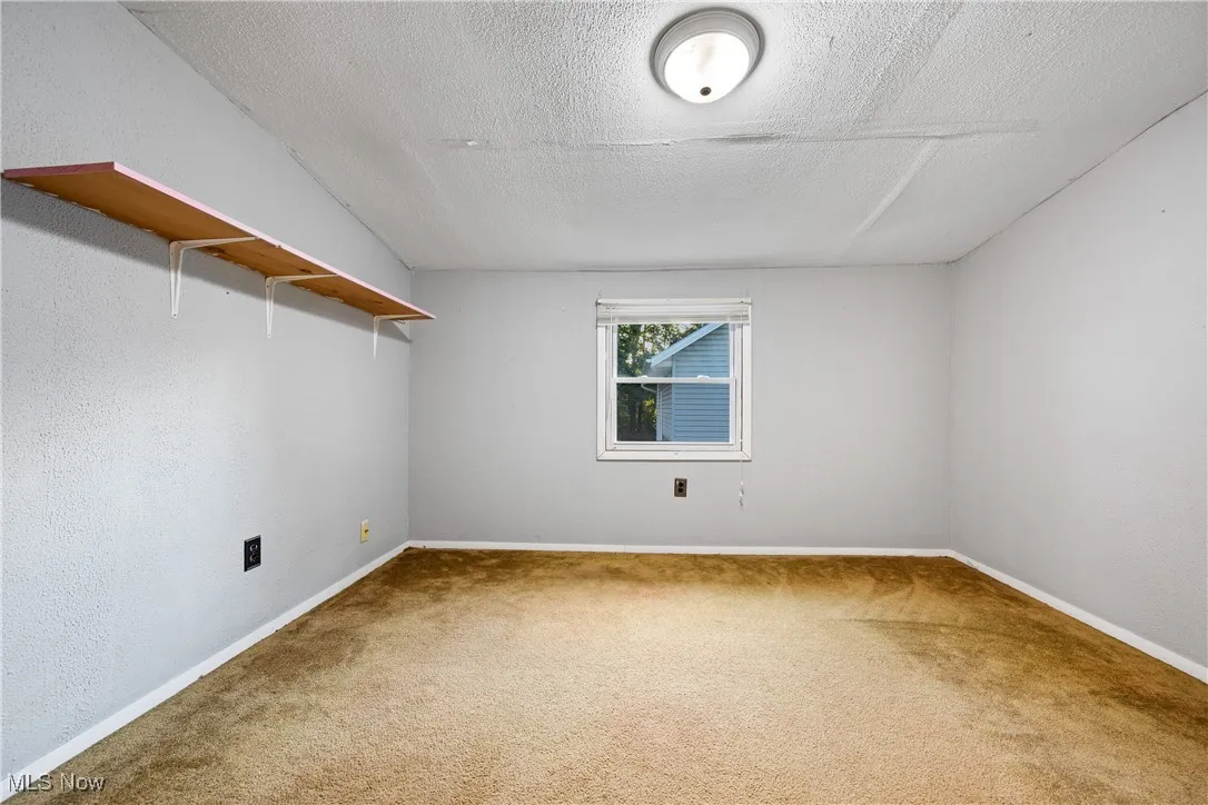 Unfurnished room with a textured ceiling, carpet flooring, and a textured wall