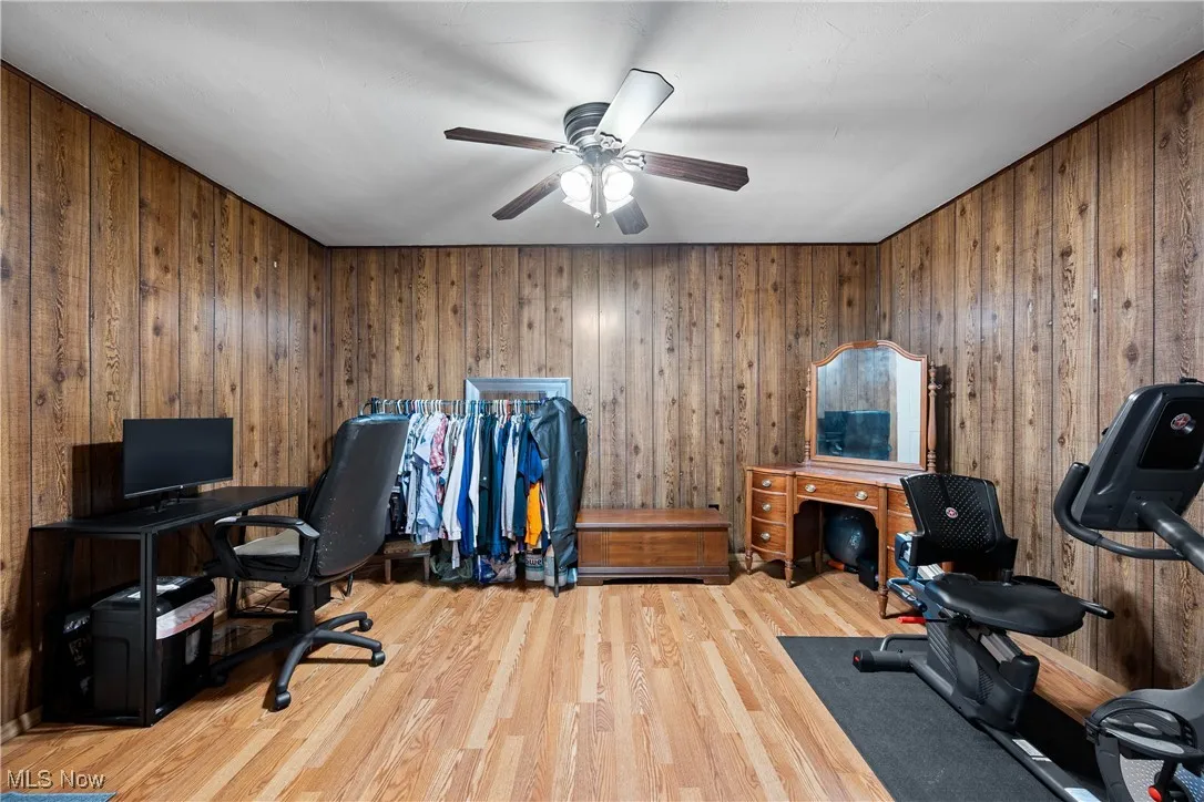 Office space with wood finished floors, wood walls, and ceiling fan