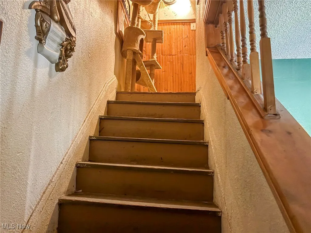 Staircase featuring a textured​​‌​​​​‌​​‌‌​‌‌​​​‌‌​‌​‌​‌​​​‌​​ wall
