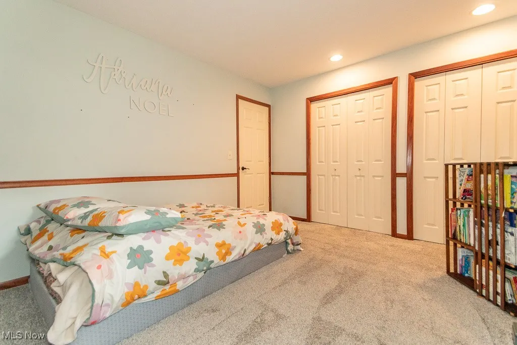 Carpeted bedroom with recessed lighting and two closets