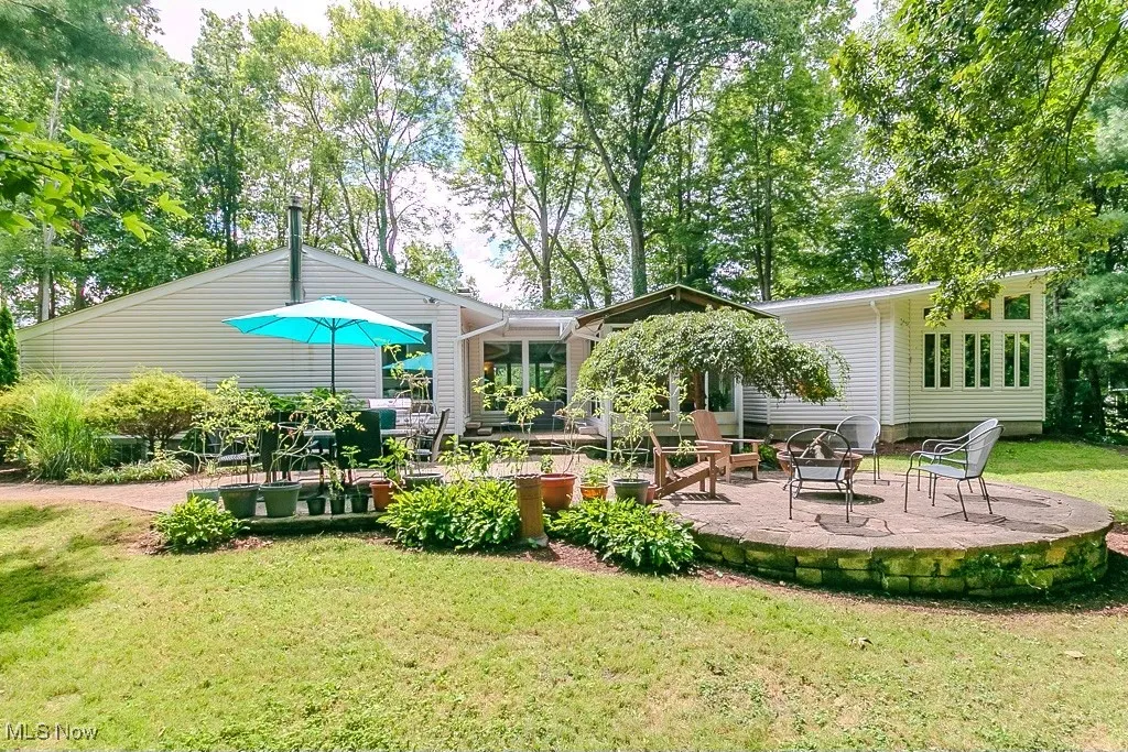 Back of house featuring a patio area, view of wooded area, and a lawn