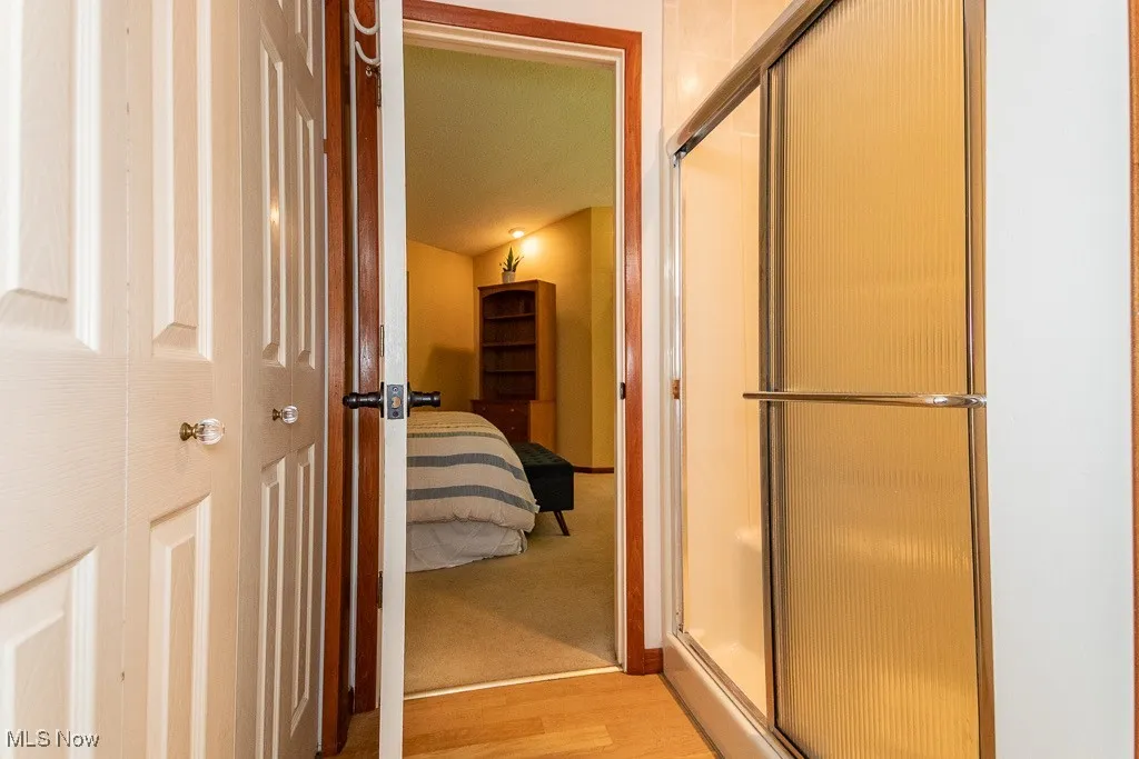Bathroom with a shower stall, light wood-style flooring, and connected bathroom
