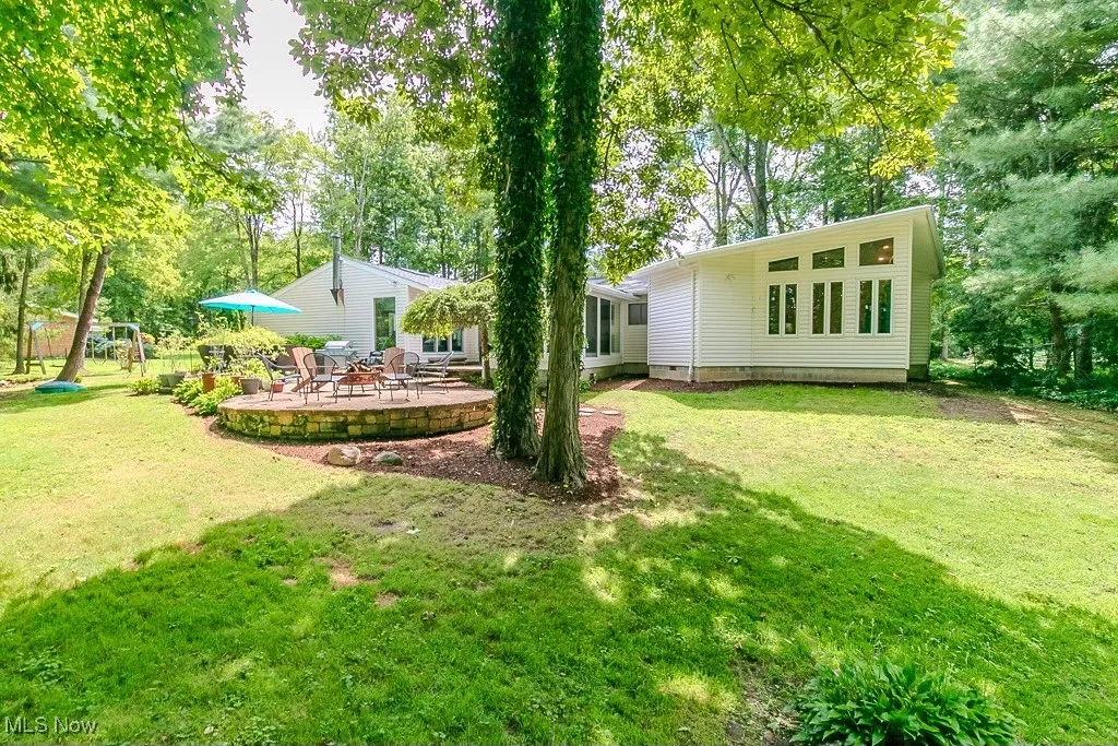 View of green lawn with view of scattered trees, a deck, and a playground