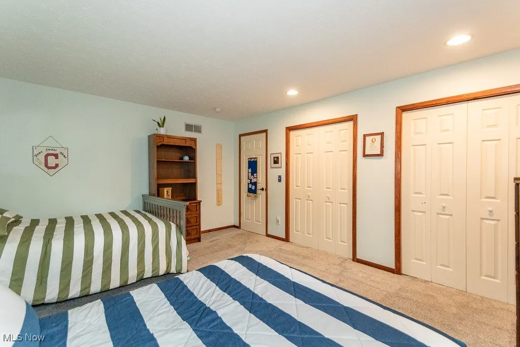 Carpeted bedroom with multiple closets and recessed lighting