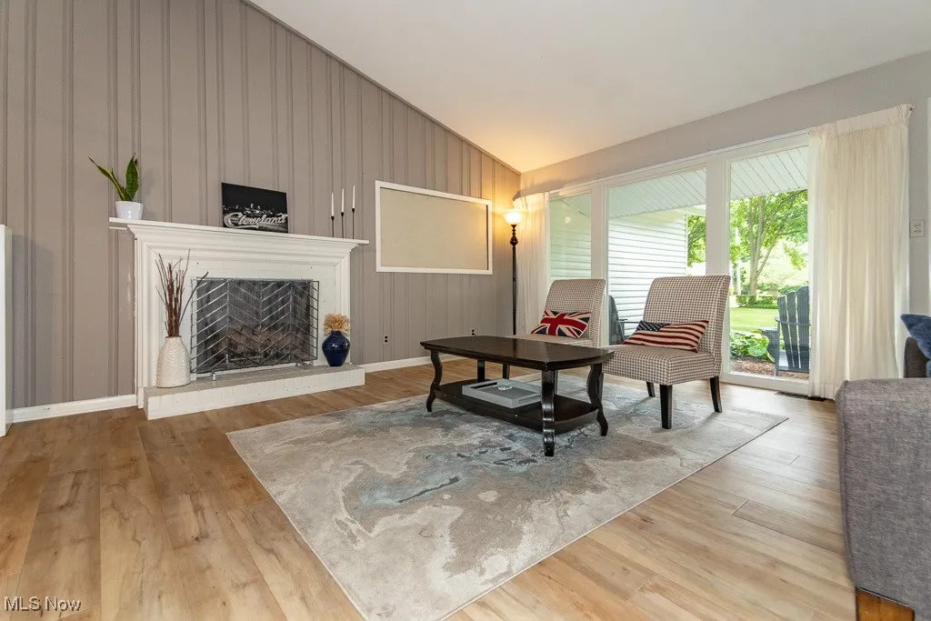 Living room with light wood-type flooring, a fireplace with raised hearth, and lofted ceiling