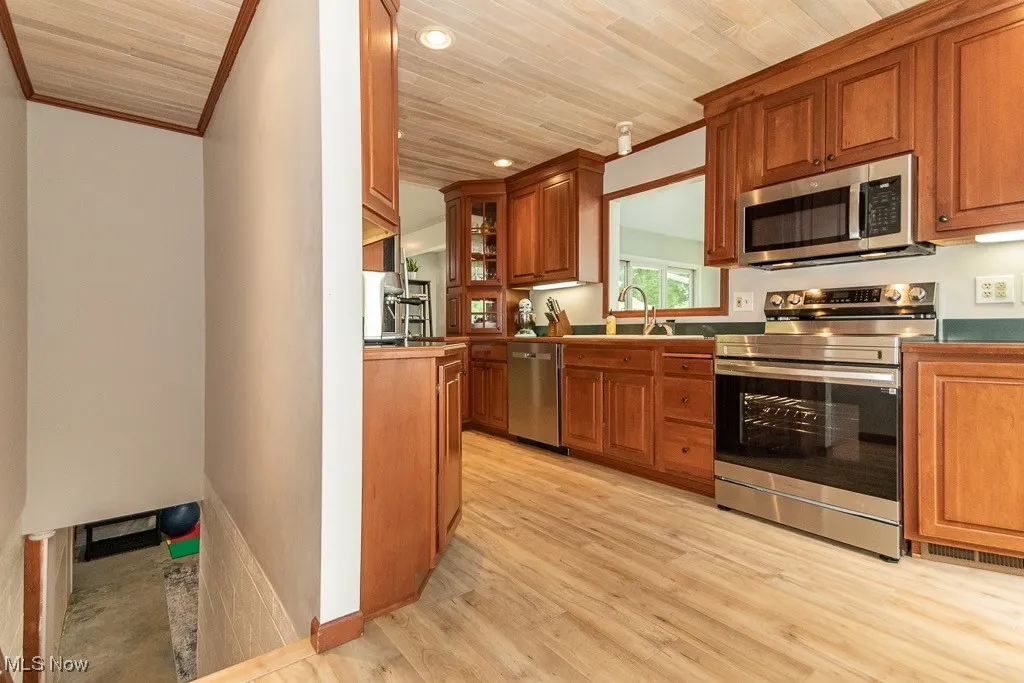 Kitchen featuring stainless steel appliances, brown cabinetry, ornamental molding, wooden ceiling, and recessed lighting