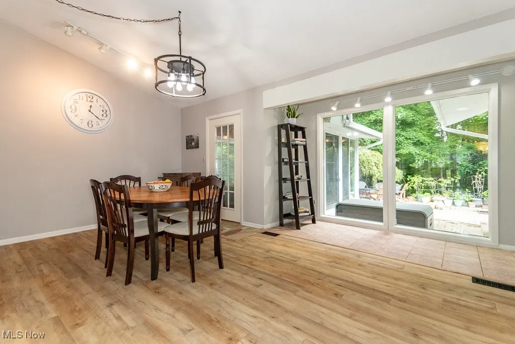 Dining room with light wood-style flooring, a chandelier, and vaulted ceiling
