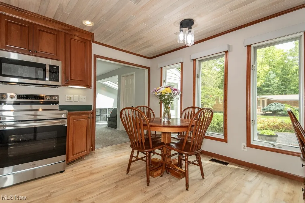 Dining room featuring light wood-type flooring, crown molding, recessed lighting, and wooden ceiling