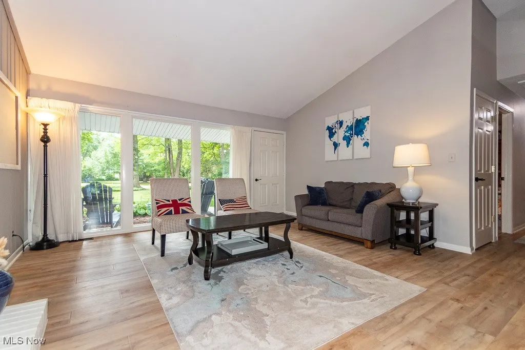 Living area with light wood-type flooring and high vaulted ceiling