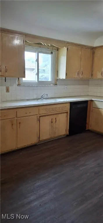 Kitchen with light countertops, decorative backsplash, dark wood-style flooring, and dishwasher