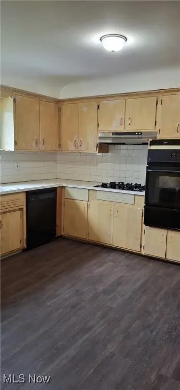 Kitchen with dark wood-style flooring, light countertops, decorative backsplash, black appliances, and a warming drawer