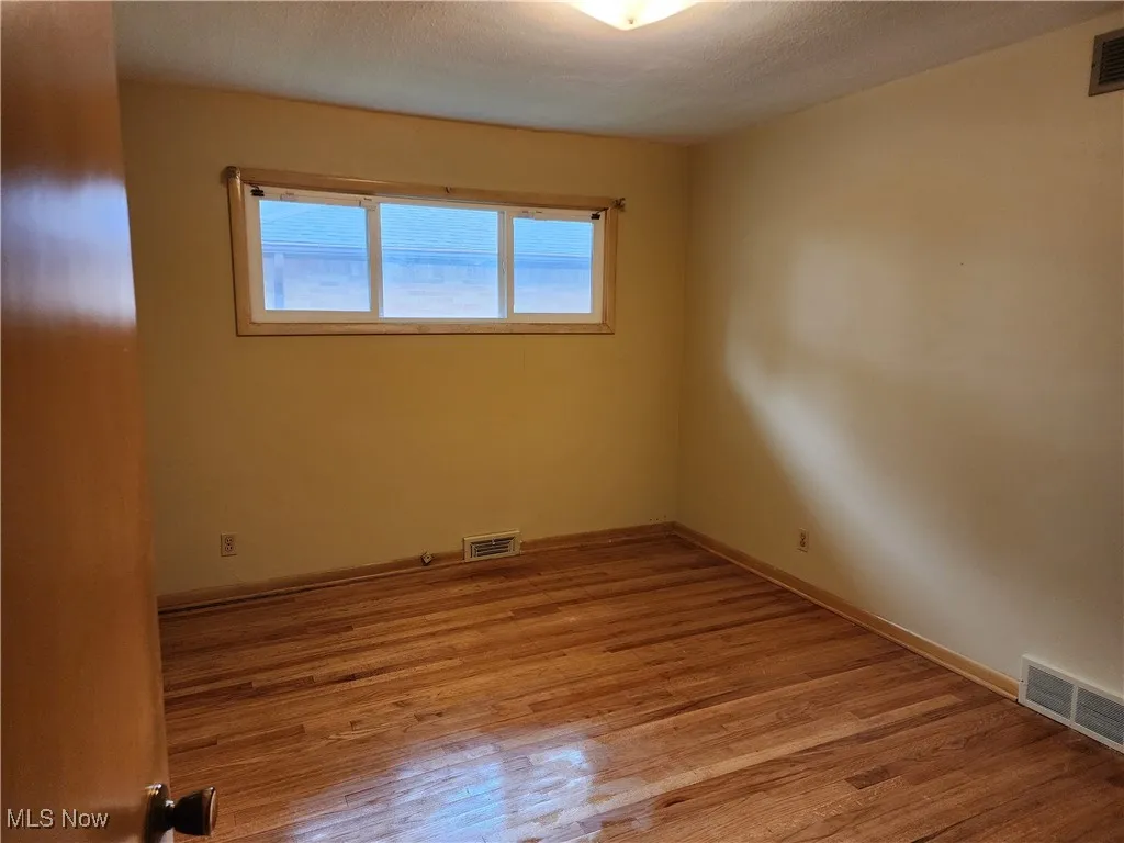 Unfurnished room featuring light wood finished floors and baseboards