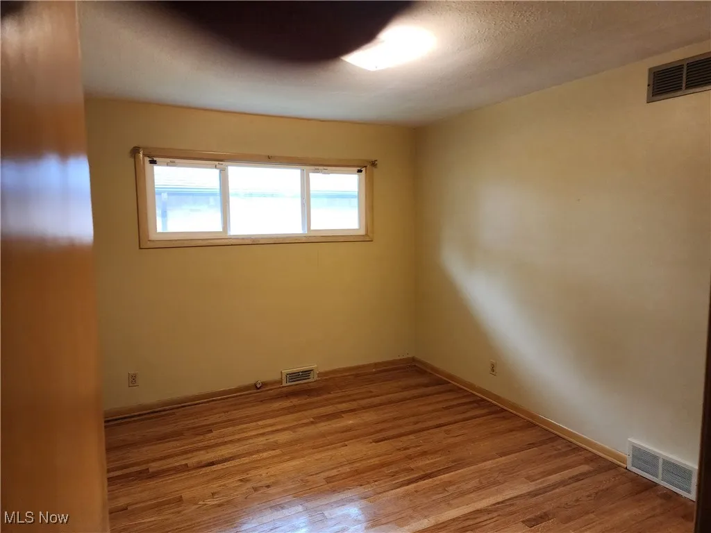 Empty room featuring light wood-style floors and a textured ceiling