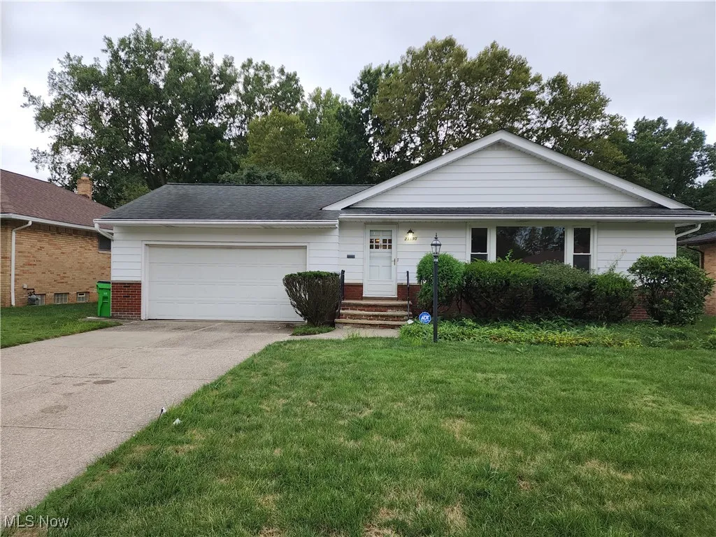 Single story home featuring a garage, driveway, brick siding, and a front yard