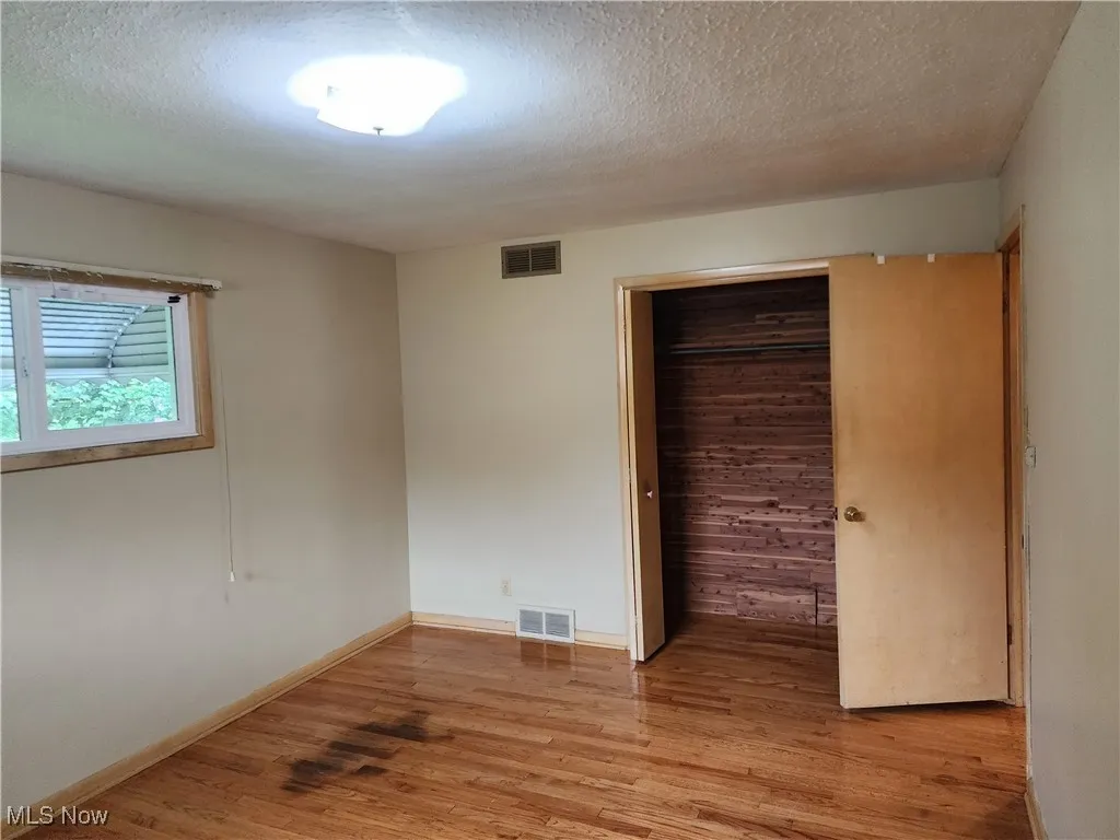 Unfurnished room with a textured ceiling and light wood-style floors
