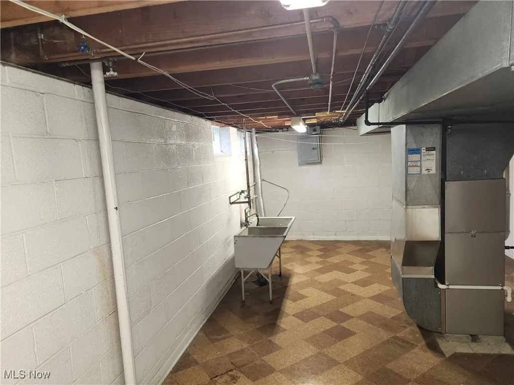 Basement featuring dark floors, heating unit, and electric panel