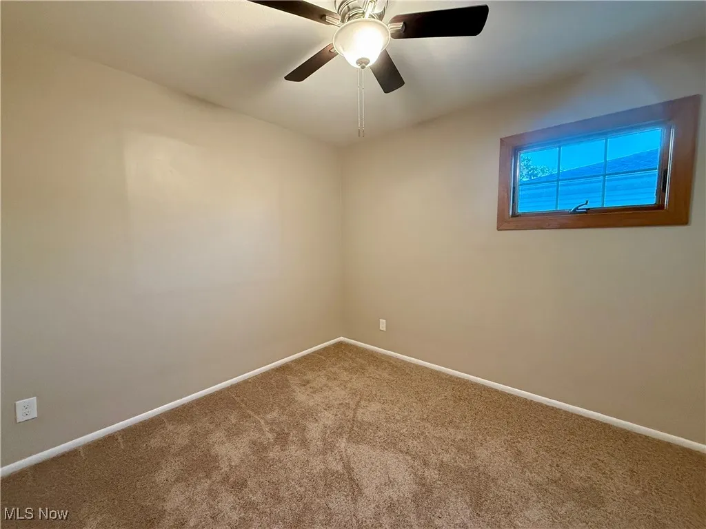 Carpeted spare room featuring baseboards and a ceiling fan