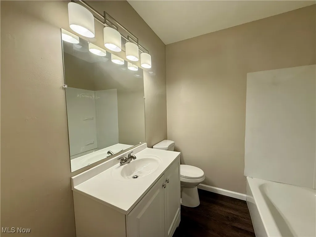 Bathroom with dark wood-style floors, vanity, and a bath