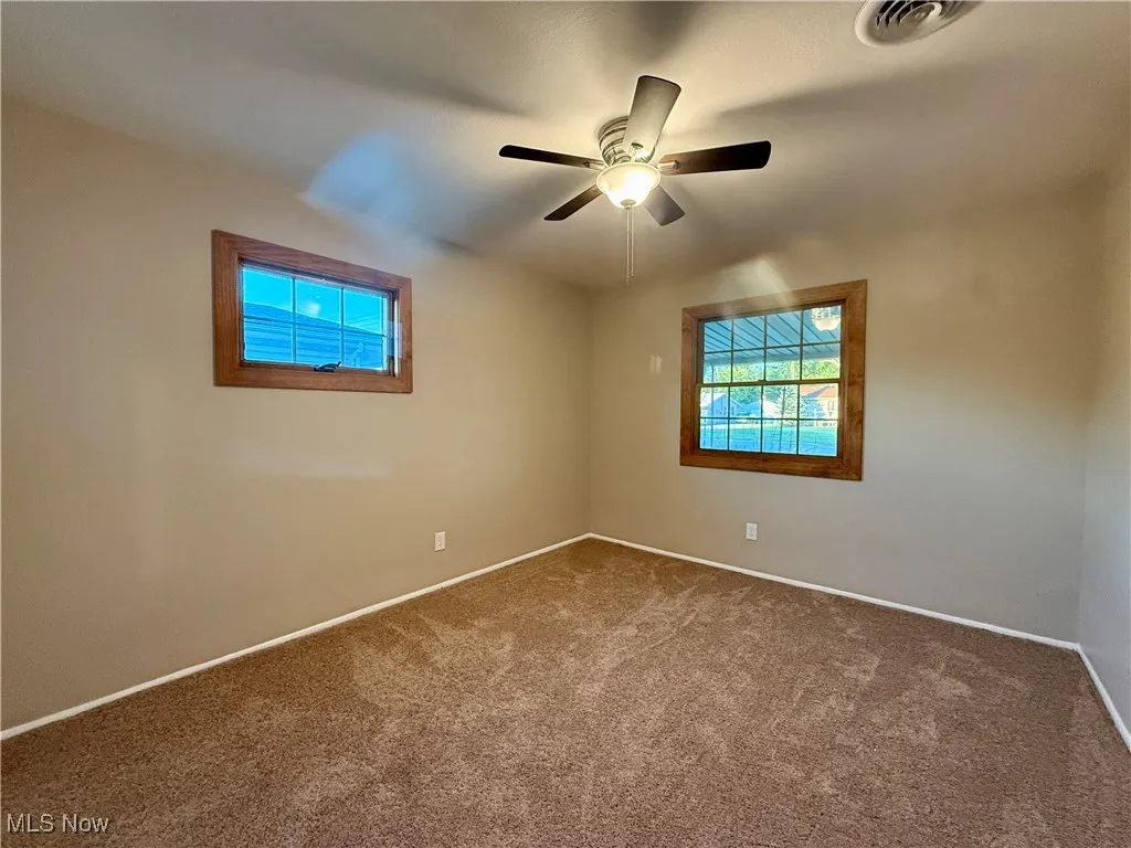 Carpeted spare room with baseboards and a ceiling fan