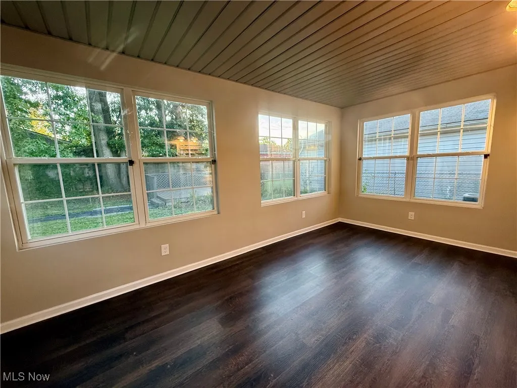 Spare room featuring plenty of natural light, dark wood-style floors, and wooden ceiling