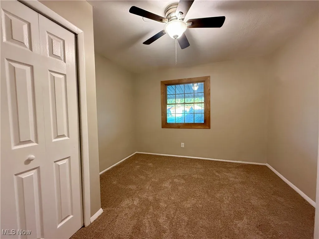 Carpeted empty room featuring baseboards and ceiling fan