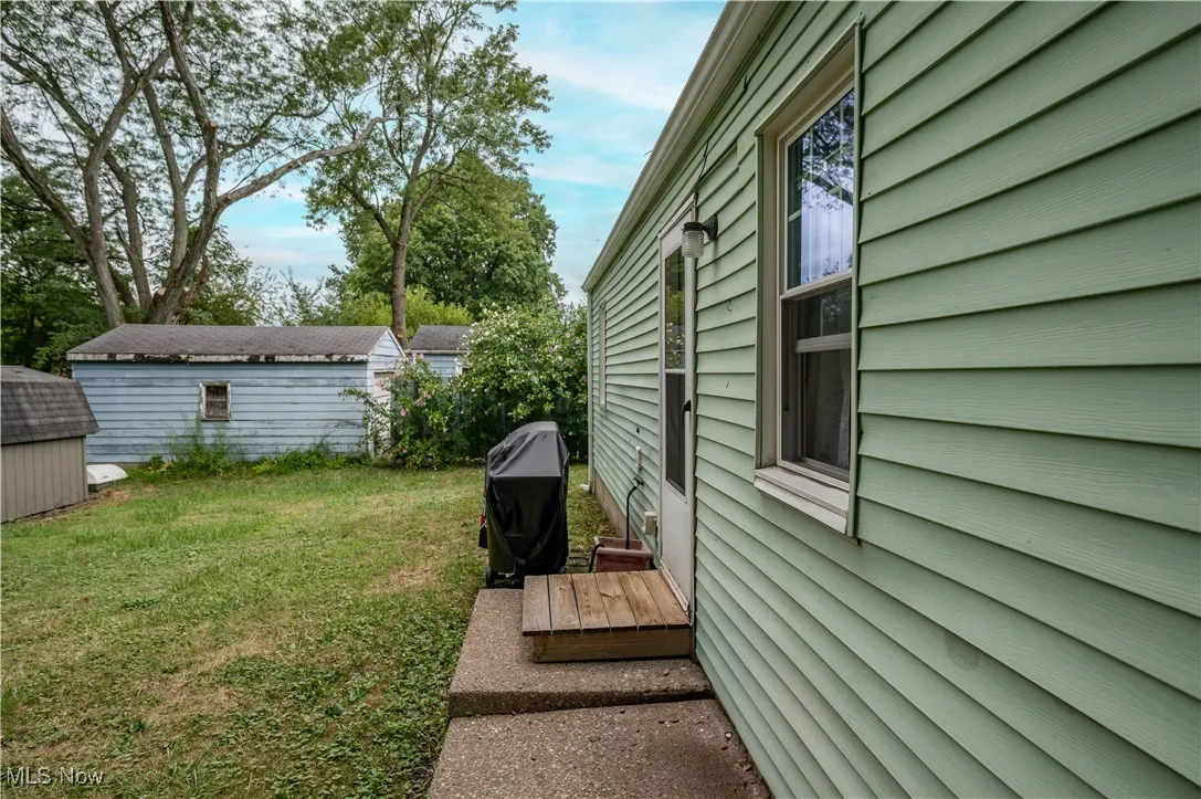 View of property exterior featuring a lawn and a storage shed