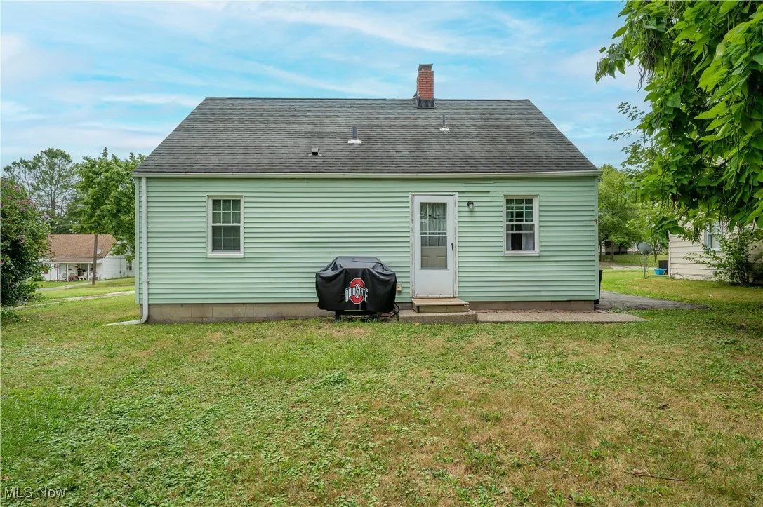 Back of property featuring a lawn, a chimney, and roof with shingles