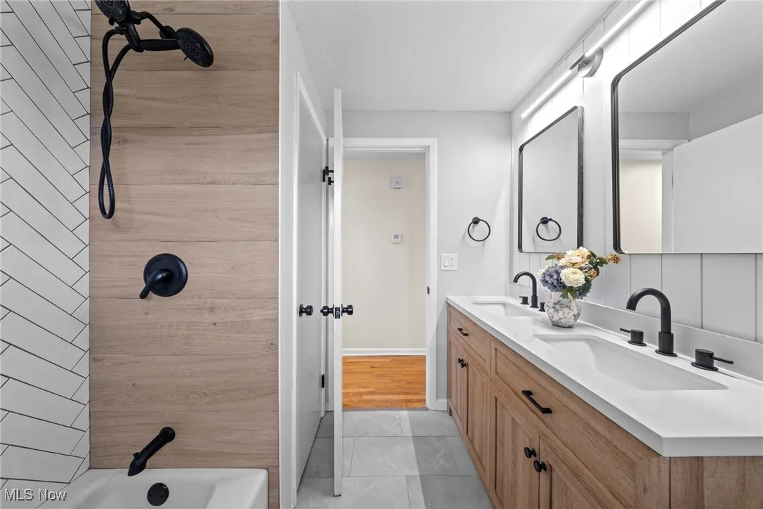 Bathroom featuring double vanity, shower / tub combination, and light tile patterned flooring