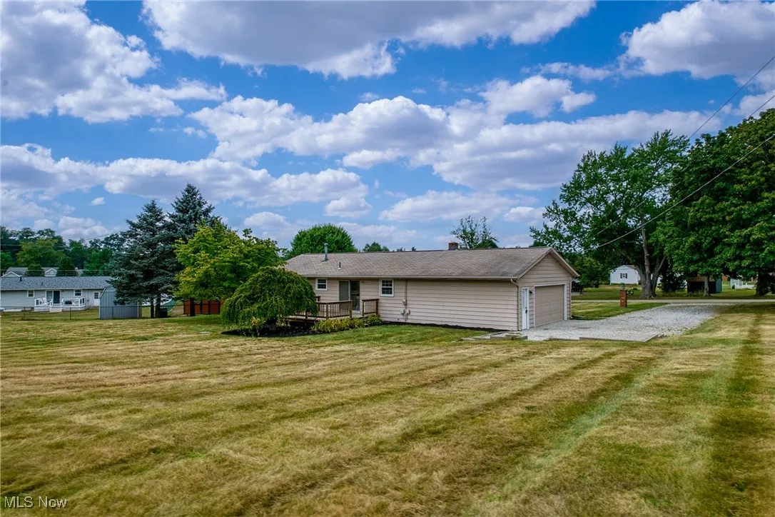 Rear view of property with driveway, a chimney, and an attached garage
