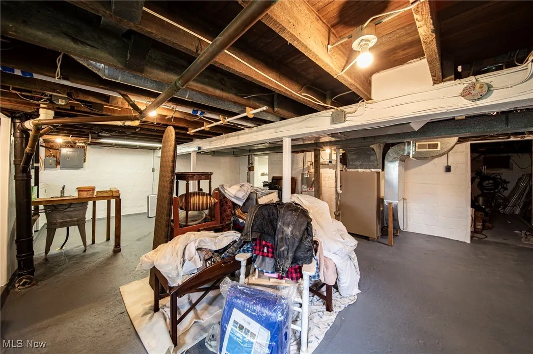 Unfinished below grade area featuring heating unit and electric panel