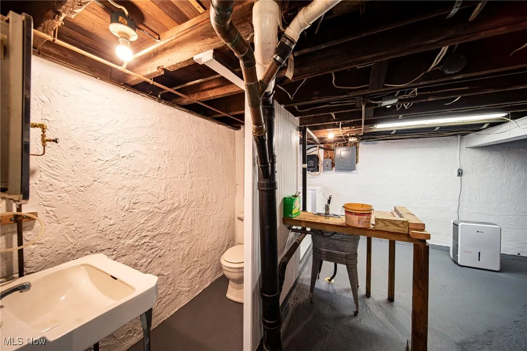 Unfinished below grade area featuring a textured wall and electric panel