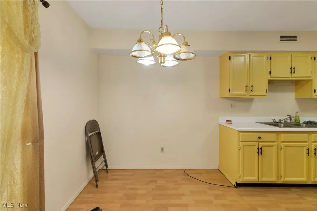 Kitchen with light countertops, decorative light fixtures, a chandelier, and light wood-style floors