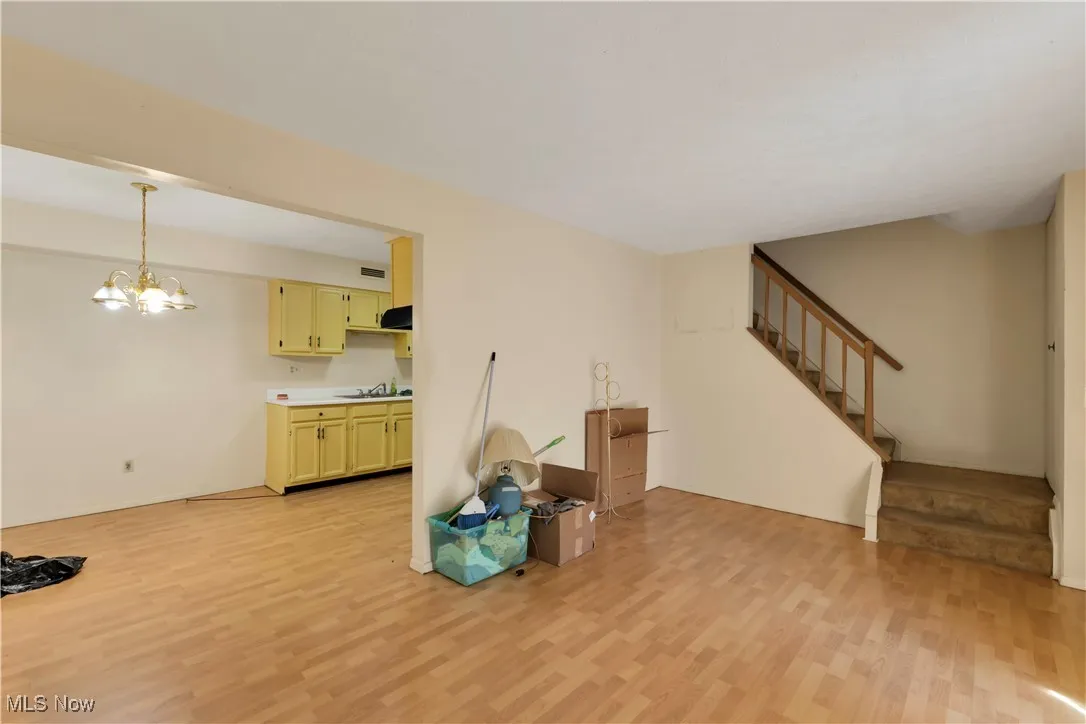 Unfurnished living room featuring light wood-style flooring, a chandelier, and stairs