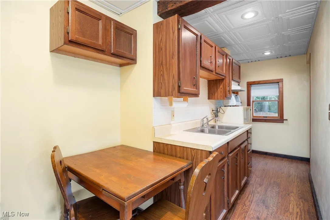 Kitchen with brown cabinets, dark wood finished floors, light countertops, recessed lighting, and backsplash
