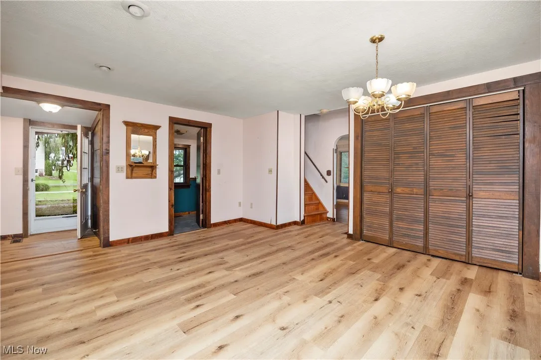 Unfurnished dining area with light wood-type flooring, arched walkways, a chandelier, and stairway
