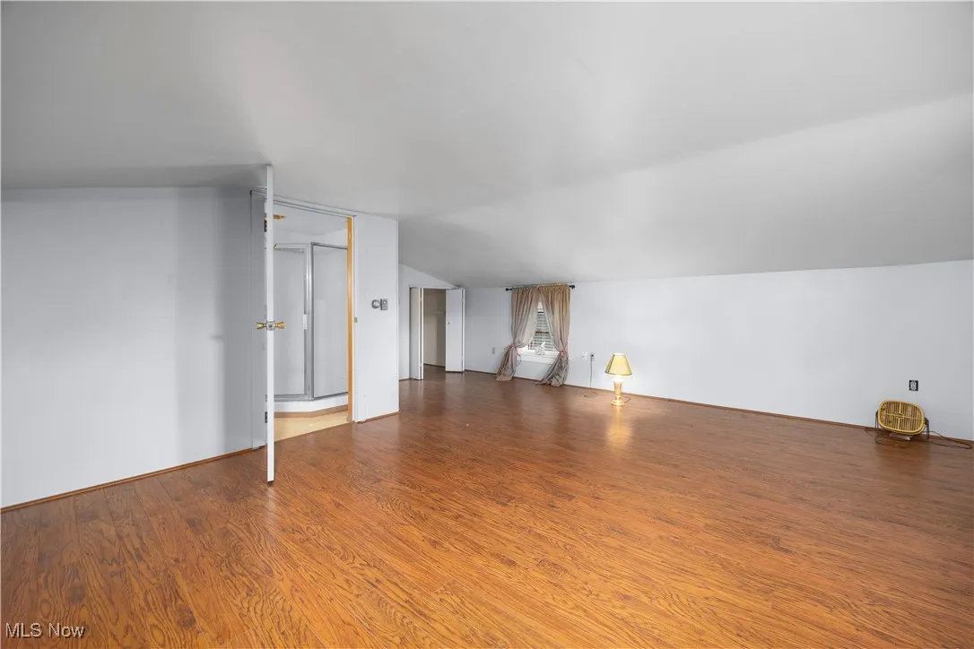 Additional living space with wood finished floors and lofted ceiling