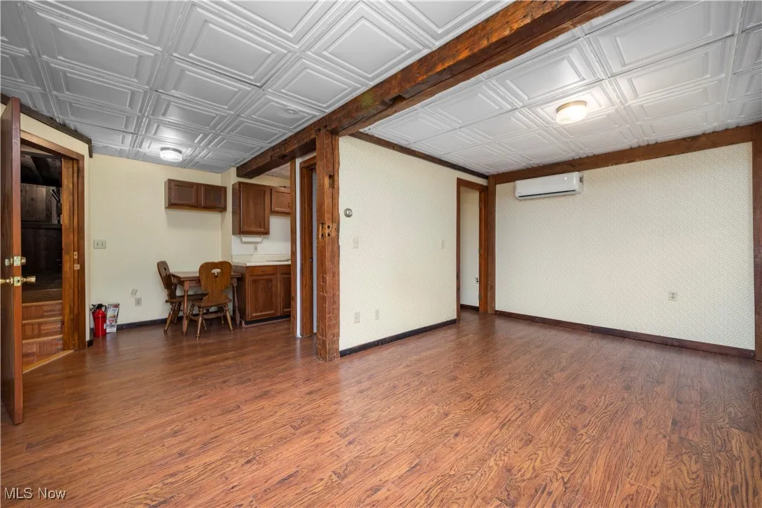 Living room featuring dark wood-type flooring, an ornate ceiling, and an AC wall unit